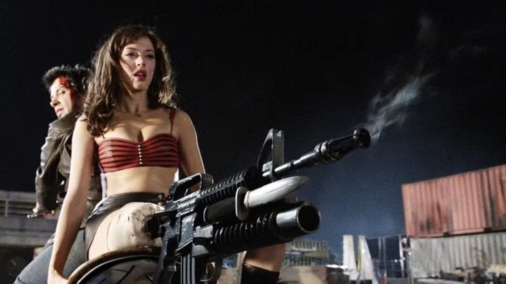 Rose McGowan points her gun leg at a zombie in Planet Terror