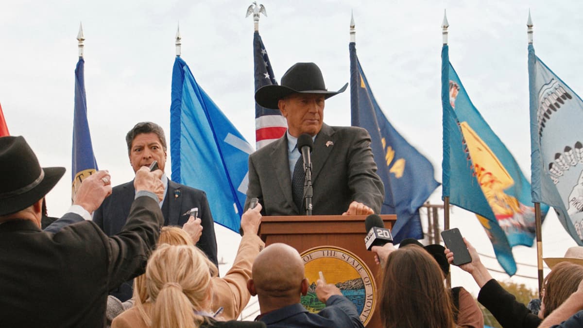 Kevin Costner as John Dutton in Yellowstone standing behind a podium