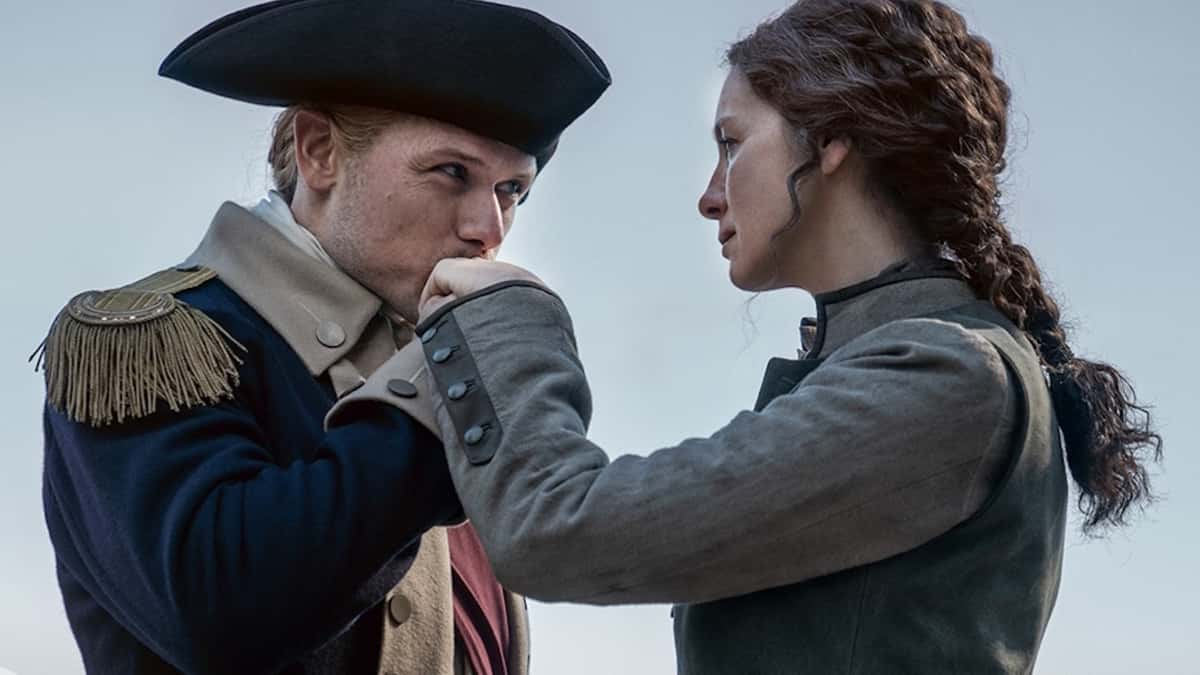 Jamie kisses Claire's hand in Outlander.