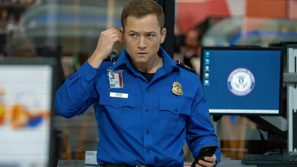 Taron Egerton holding his ear-piece in Carry-On.