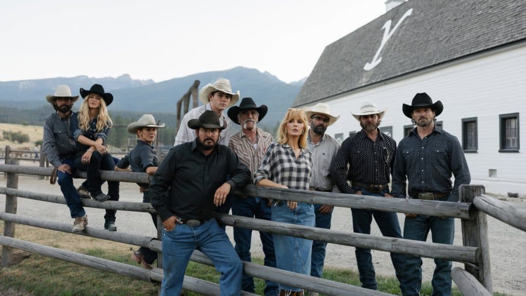 The cast of Yellowstone standing outside the stable