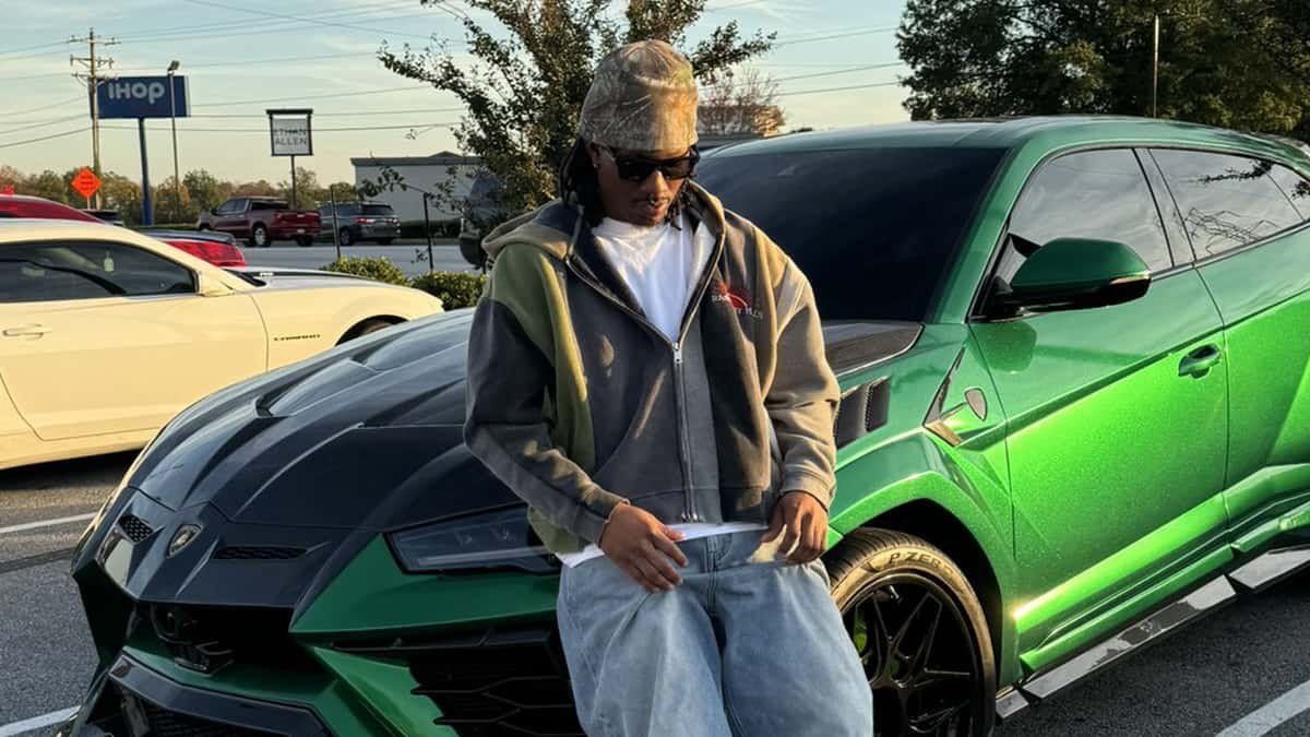 Duke Dennis standing against his green lamborghini urus