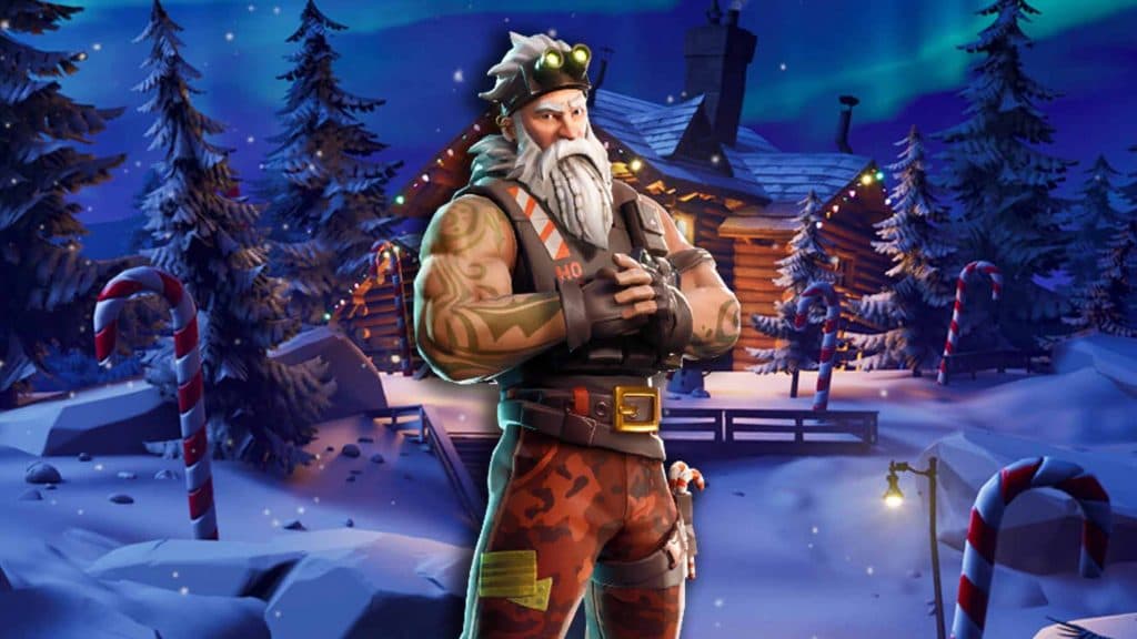 Sgt. Winter, a muscely man with tattoos and a white beard, standing outside of a log cabin