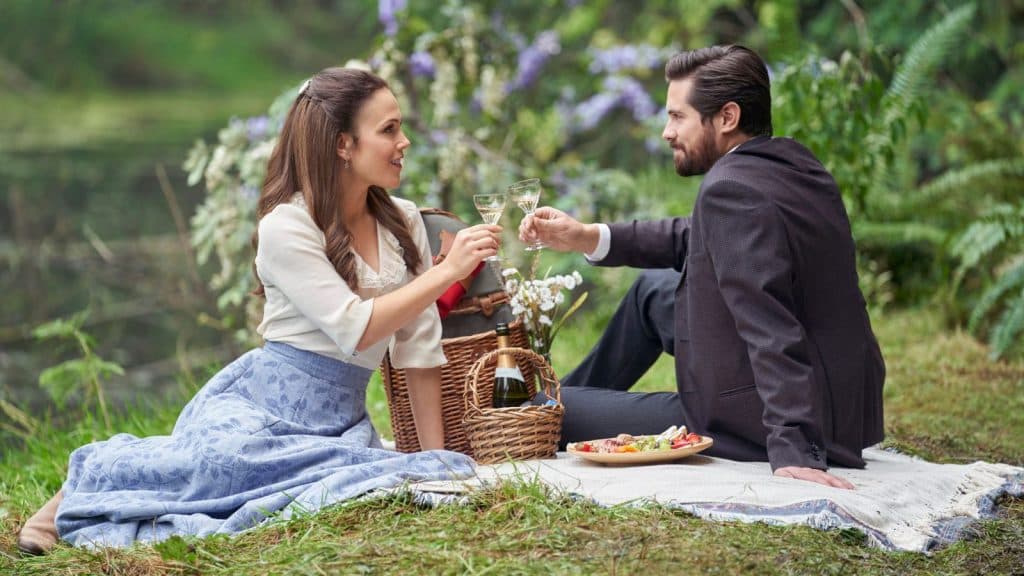 Elizabeth and Lucas toast glasses at a picnic in When Calls the Heart