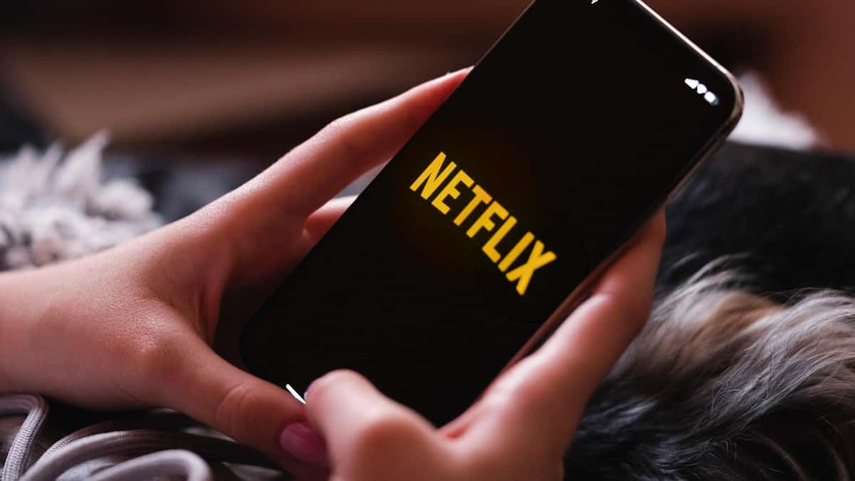 Someone using their phone with a gold Netflix logo