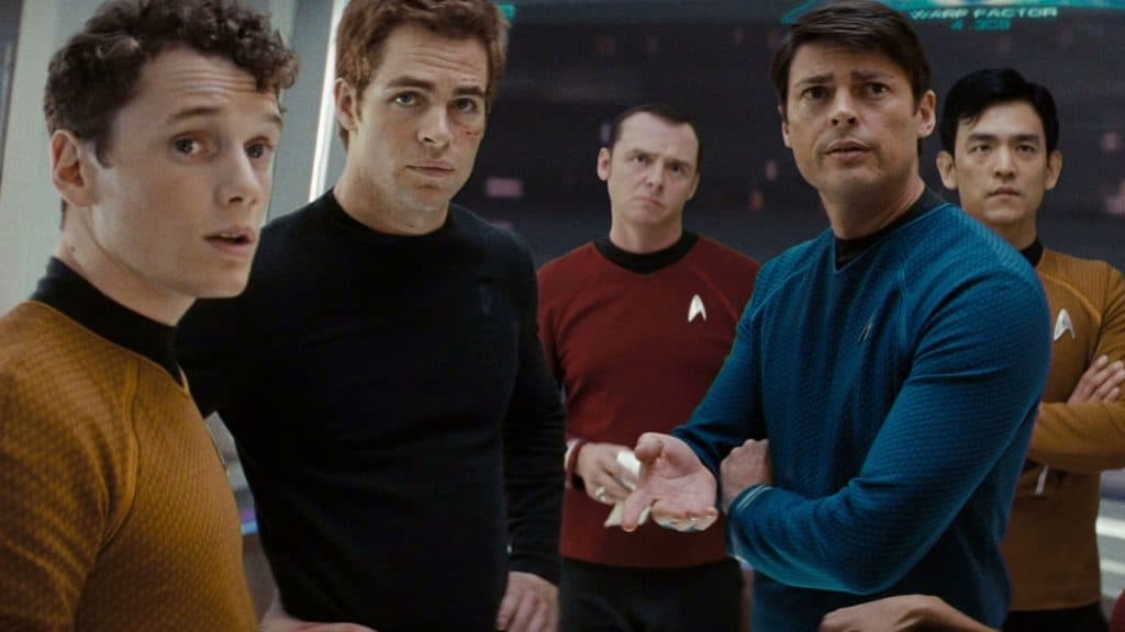 The crew of the USS Enterprise stand in a circle staring at something off screen.