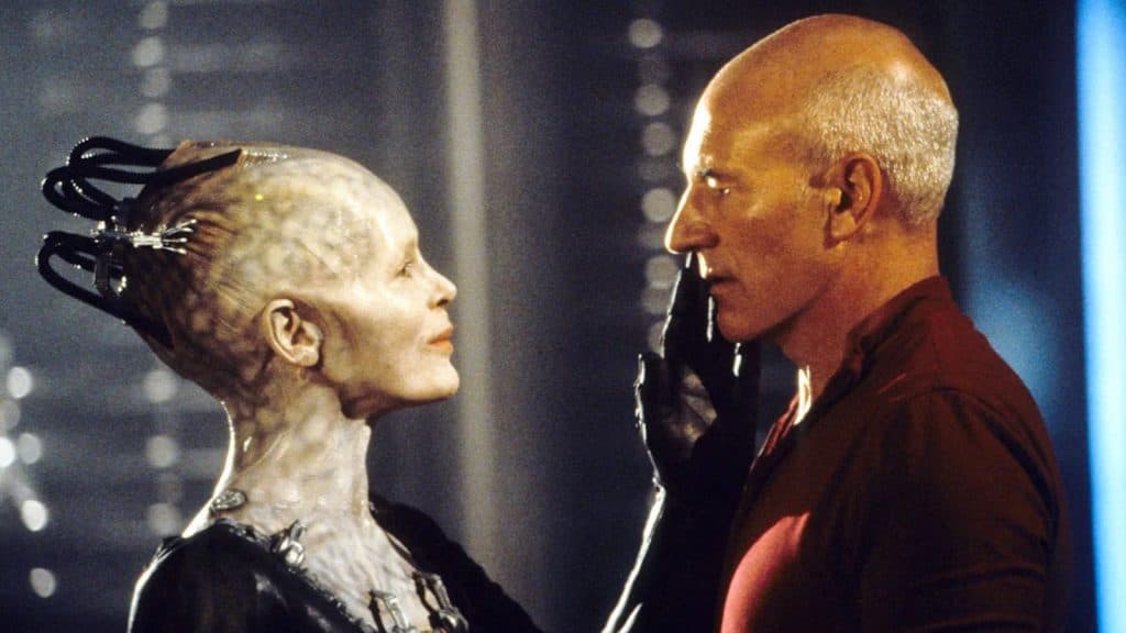 CaptaiN jean-Luc Picard stares down the Borg Queen as she strokes his face.