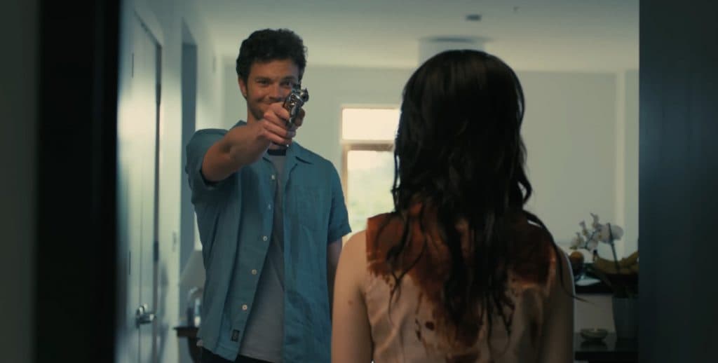 Jack Quaid holding a gun as Josh in Companion