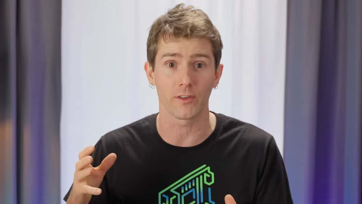 Linus Tech Tips sat with hands raised talking to camera