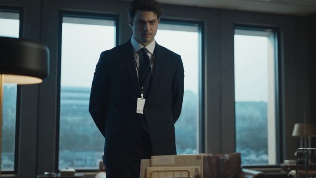 Noah Centineo in a suit in an office in The Recruit.