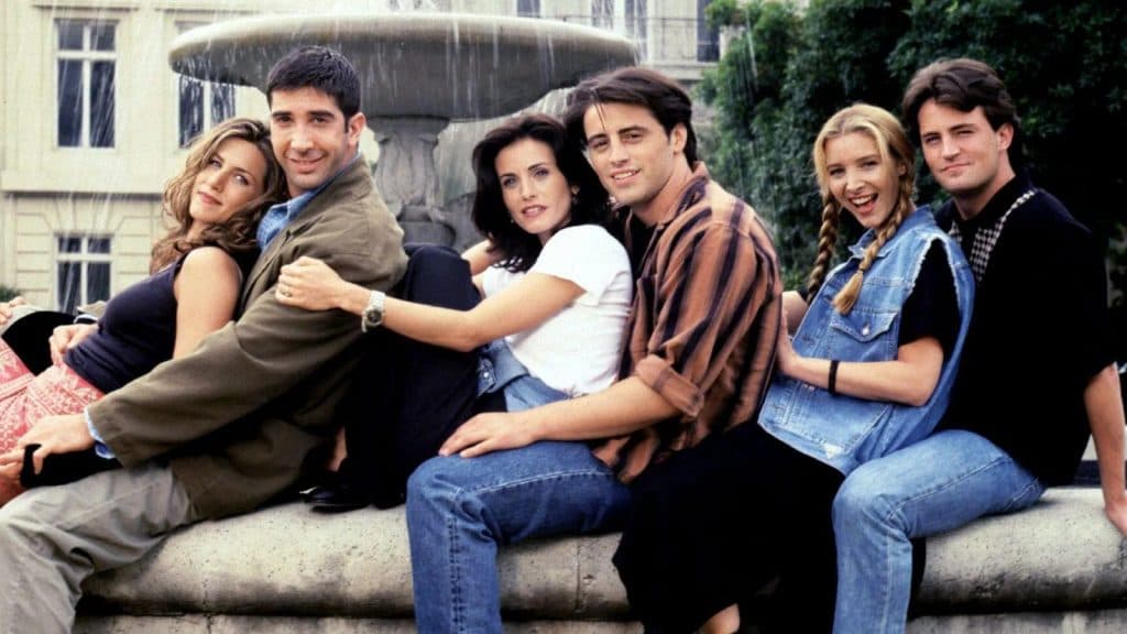 The Friends cast sitting in front of the iconic fountain.