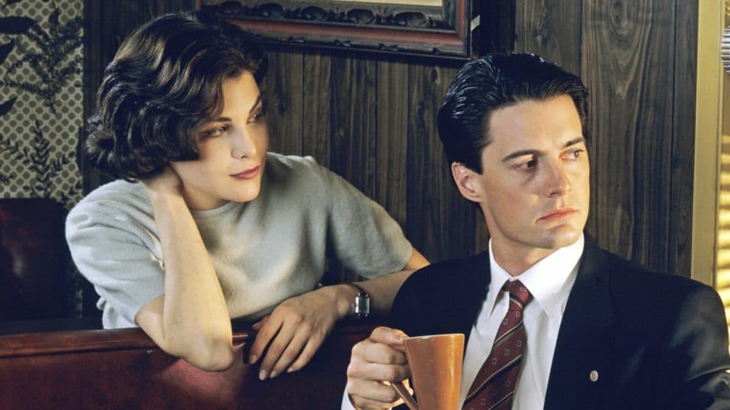 Audrey looking at Dale Cooper in a coffee shop in Twin Peaks.