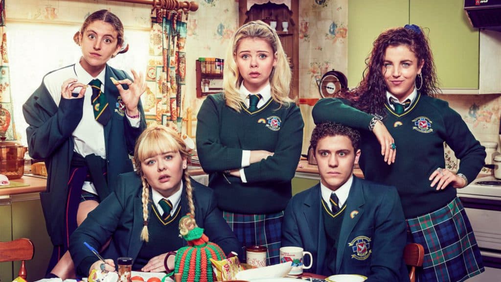 A group of girls and one boy sit at the kitchen table in Derry Girls