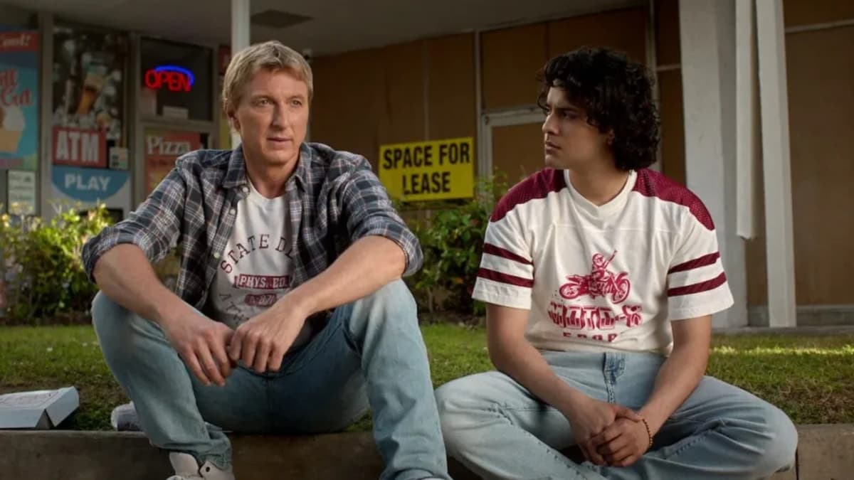 Johnny speaking with Miguel while they sit on a step in Cobra Kai.